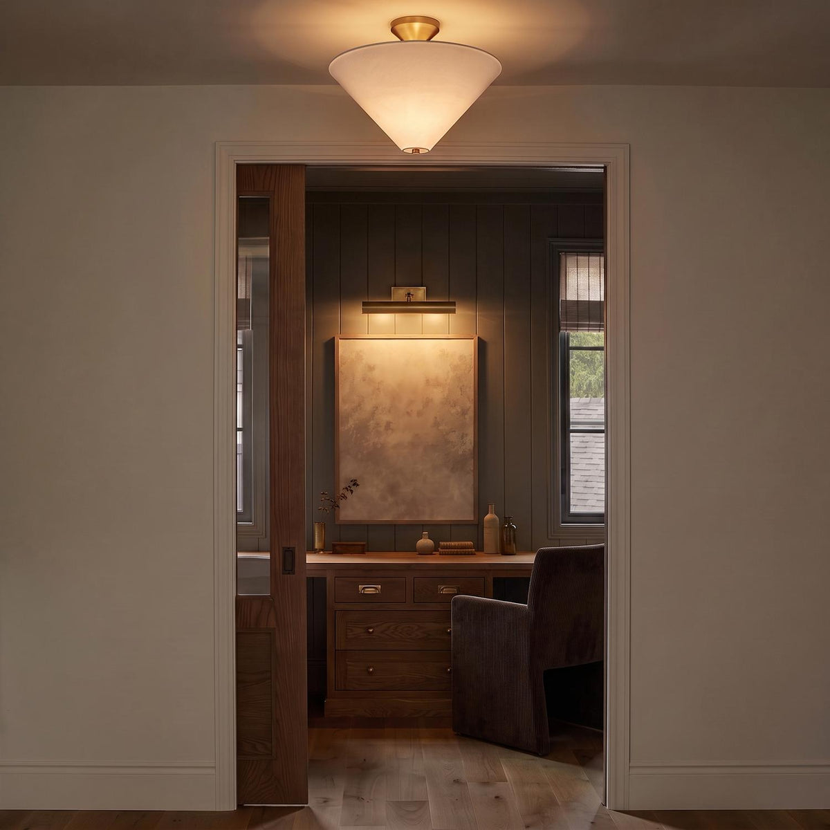 A transitional foyer with the Sabina Semi-Flush Mount 16 inch in brushed brass with a linen shade along the ceiling, looking into a wood-paneled study with a desk.