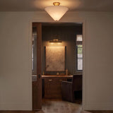 A transitional foyer with the Sabina Semi-Flush Mount 16 inch in brushed brass with a linen shade along the ceiling, looking into a wood-paneled study with a desk.