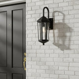 Black Asbury Outdoor Wall Light, Small 23" tall on a white brick wall next to a black door.