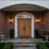 Asbury Outdoor Wall Light, Medium 29" Black - Two black lantern-style sconces illuminate a brick facade flanking a double wooden door with a white arched entryway.