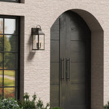 Ainsley Outdoor Wall Light, Large 24" in Oiled Bronze finish is shown next to an arched front door, on a sand colored stone house.