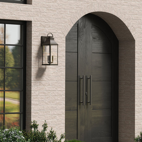 Ainsley Outdoor Wall Light, Large 24" in Oiled Bronze finish is shown next to an arched front door, on a sand colored stone house.