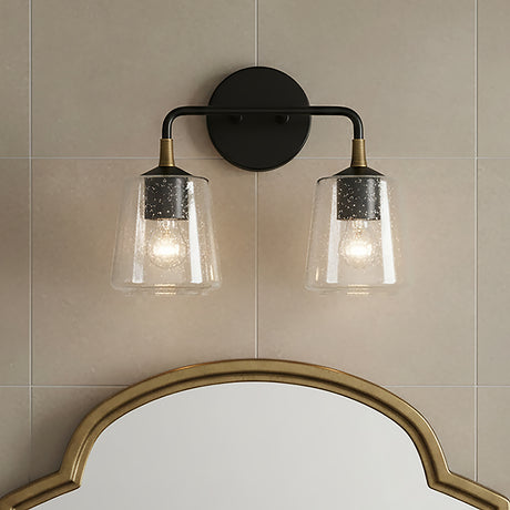Malin 2 Light Vanity - Two lights with seeded glass shades and brass accents on a matte black fixture against a tiled wall, above a decorative mirror.
