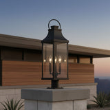Ainsley Outdoor Post Light, Black - Black post light on a stone pillar with a building in the background