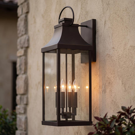 A Mediterranean home exterior featuring the Ainsley Outdoor Wall Light, Extra Large 27" Oiled Bronze lantern glowing at dusk on a stucco wall beside a stone corner.