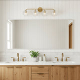 Ori 4 Light Vanity, Matte Brass - A bathroom vanity with a wood cabinet, white countertops, and a matte brass light fixture with four glass globes.