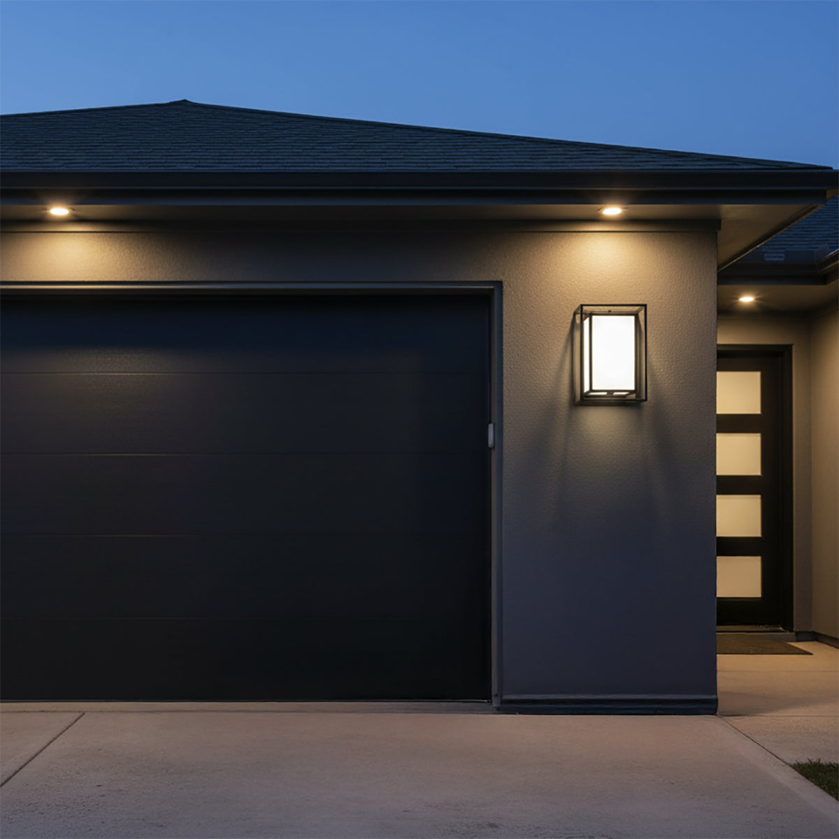 Orley Outdoor Wall Light, 16" tall in Black - A contemporary black wall light illuminates the exterior of a modern home next to a garage door.