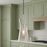 A transitional kitchen features the Aries Pendant 6", Polished Nickel with a crackle glass shade over the island, sage green shaker cabinets, and white tiled backsplash.