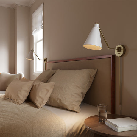 Avin Adjustable Wall Sconce, White and Aged Brass finish, is shown next to a comfy bed as a reading light.