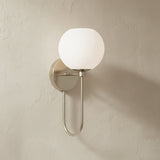 Enid Wall Sconce 15", Brushed Nickel, on a light beige plaster wall.