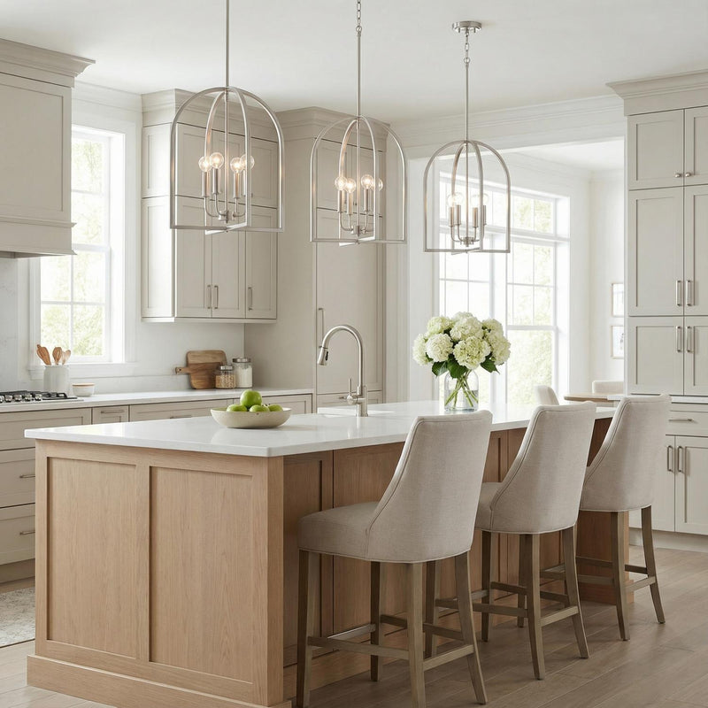 A transitional kitchen features three Elira Lantern Pendant 16", Brushed Nickel fixtures over the island with a white quartz countertop and natural wood cabinetry.
