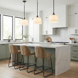 A transitional kitchen features three matte black pendants with white linen shades hanging over a white marble waterfall island and sage green lower cabinets.