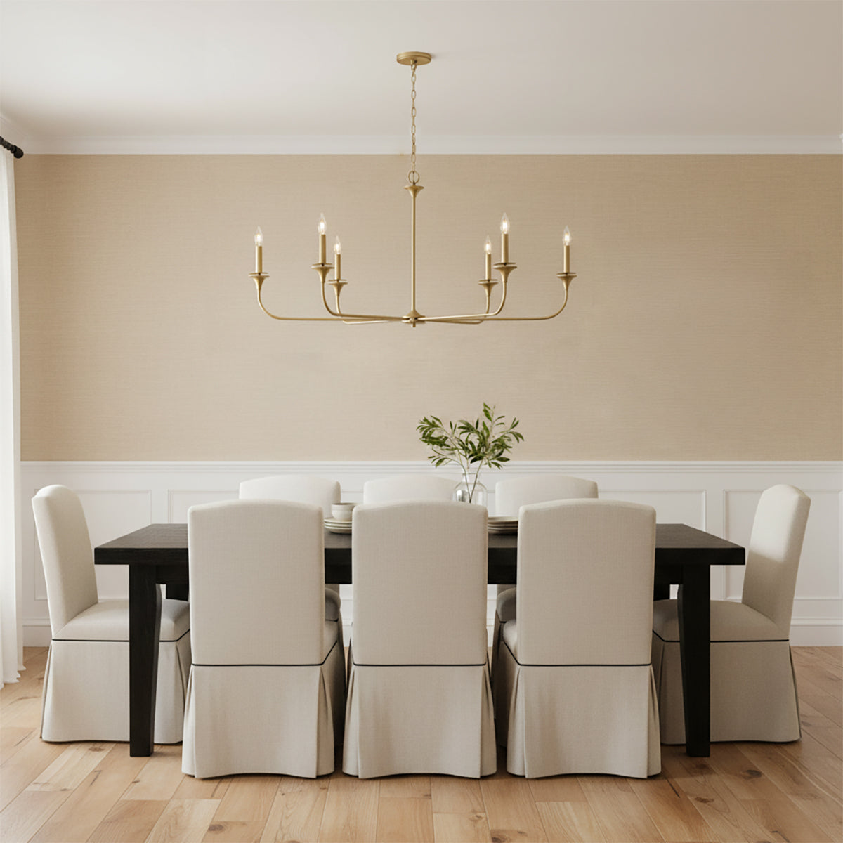 Harper 6 Light Chandelier 49, Aged Brass - A linear aged brass chandelier hangs above a dark wood dining table with upholstered chairs.
