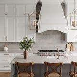 Eloise 16" Lantern Pendants in Matte Brass are shown in a modern farmhouse kitchen hung above the island, with wood and rattan bar stools.