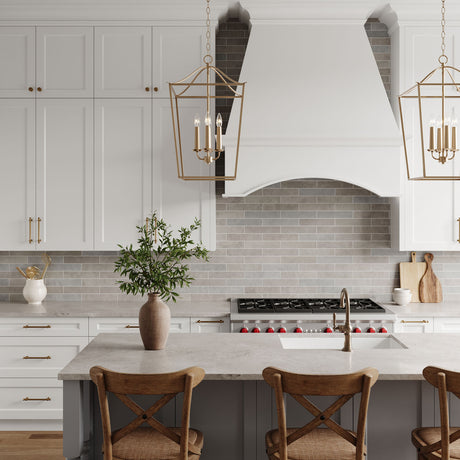 Eloise 16" Lantern Pendants in Matte Brass are shown in a modern farmhouse kitchen hung above the island, with wood and rattan bar stools.
