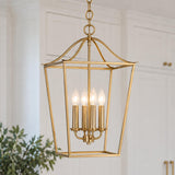 A transitional kitchen features the Eloise Lantern Pendant 16", Matte Brass suspended in front of white paneled cabinetry with brass hardware and greenery.