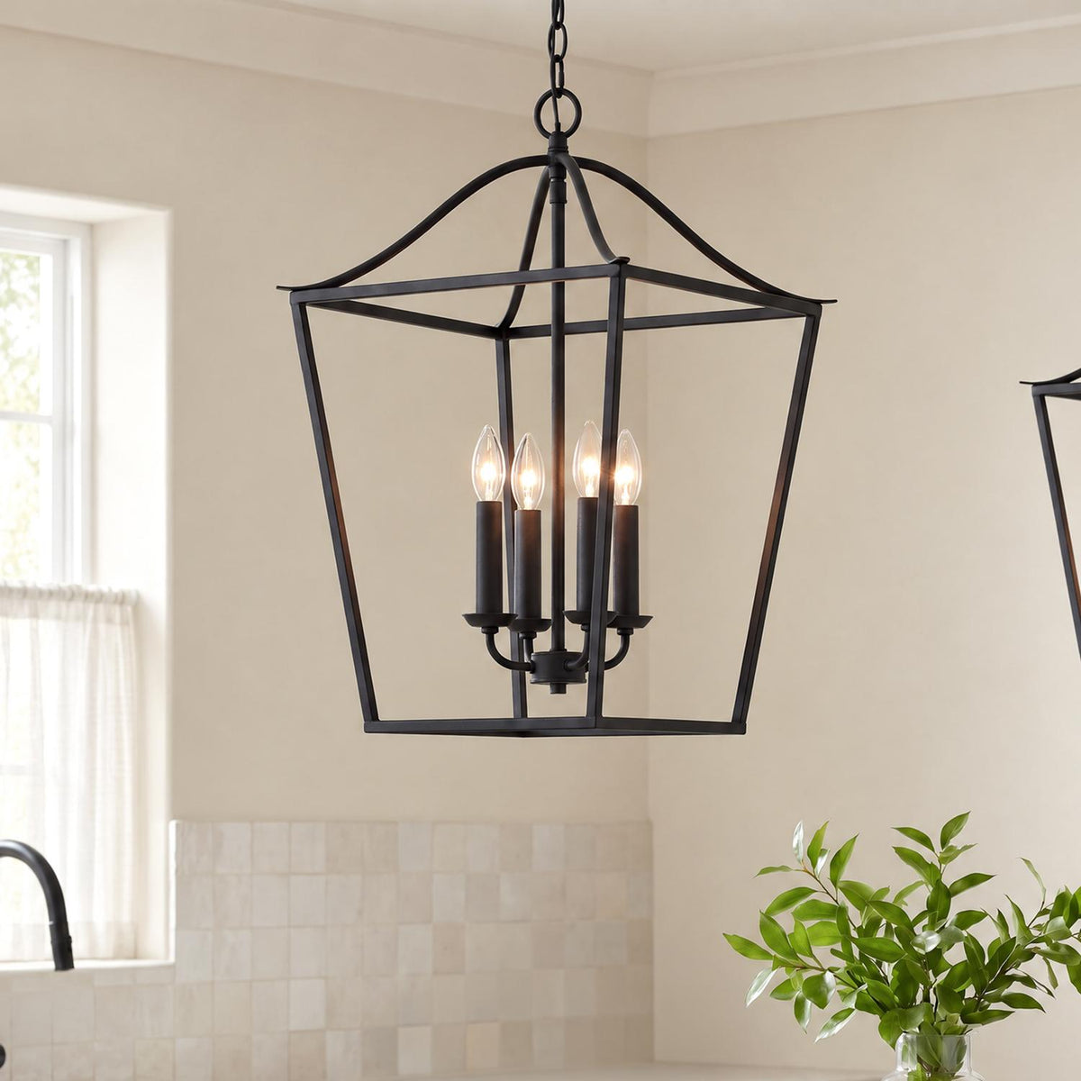 A transitional kitchen features an Eloise Lantern Pendant 16", Textured Black suspended above a counter beside an off-white square tile backsplash and window.