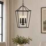 A transitional dining room with the Eloise Lantern Pendant 16", Textured Black hanging over a table with green foliage in a ceramic vase.