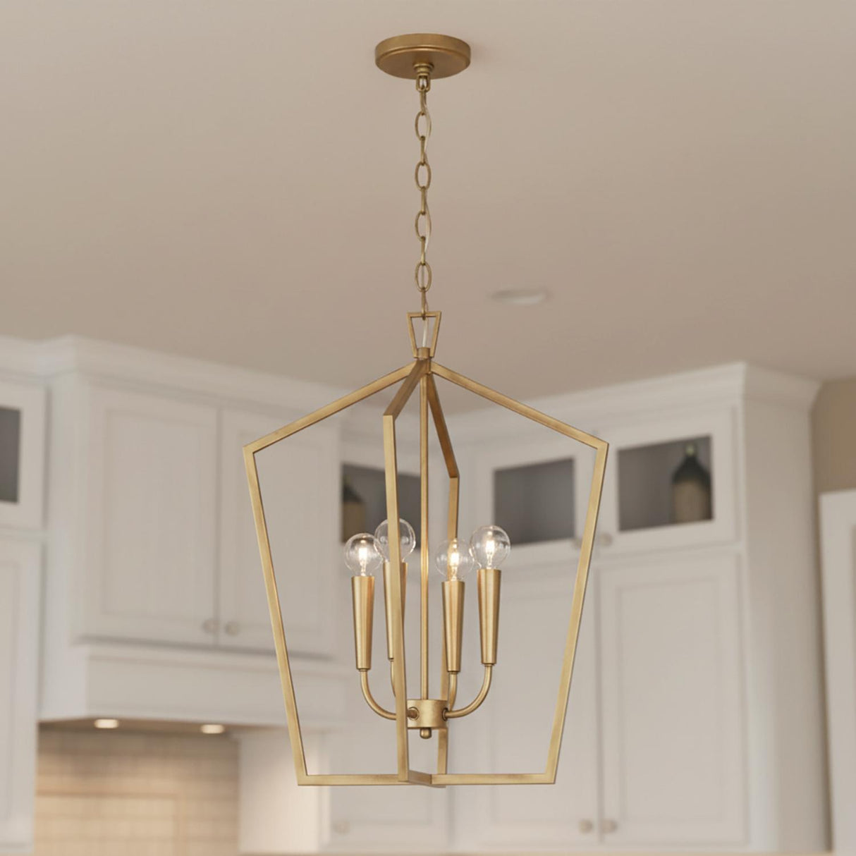 A transitional kitchen featuring the Clara Lantern Pendant 17", Aged Brass hanging along the ceiling with white cabinetry and a tiled backsplash.