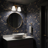 Dark bathroom with navy and tan floral wallpaper, a round mirror, and the Brier 2 Light Vanity Light above, in Aged Brass