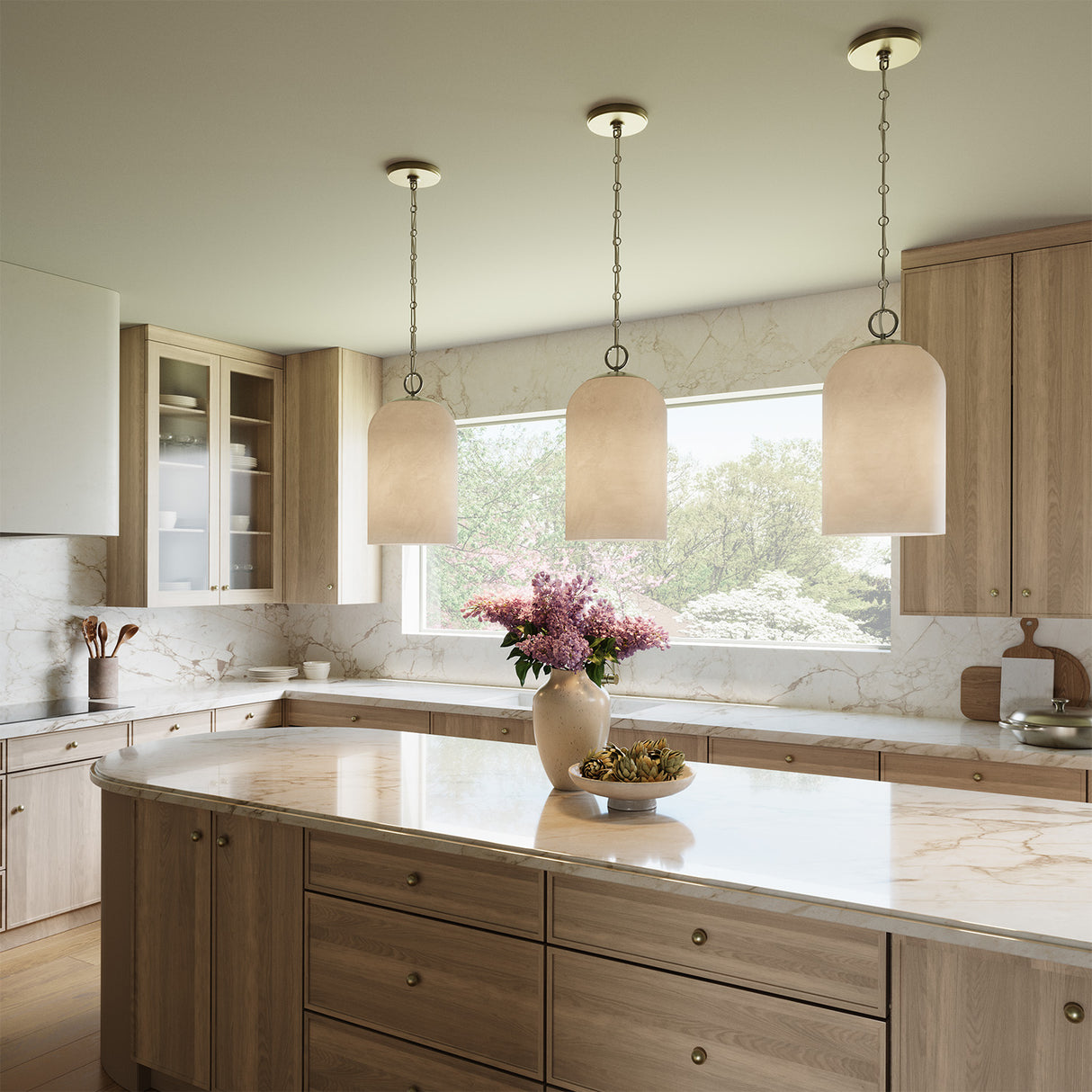 Modern kitchen with light wood cabinets, marble countertops, and three Tovi 9" wide Pendant lights, in Matte Brass with Cloud Opal Glass dome shades