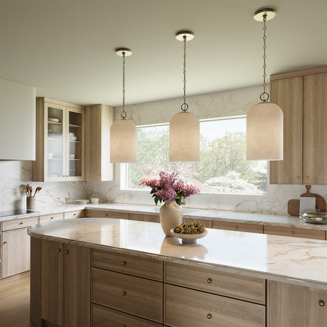 Modern kitchen with light wood cabinets, marble countertops, and three Tovi 9" wide Pendant lights, in Matte Brass with Cloud Opal Glass dome shades