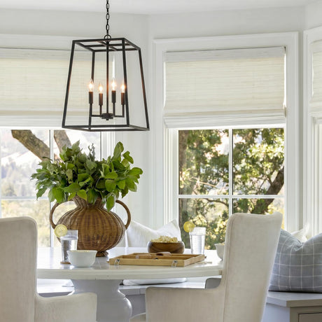 A transitional dining nook with the Tilden Lantern Pendant 21", Textured Black hanging over a white pedestal table with a large rattan vase and greenery.