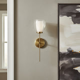 Suri 20" Wall Sconce in aged brass finish, next to a large piece of modern art .