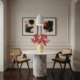 White geometric Pendant in a Transitional Dining Room with a white marble table and cane chairs.