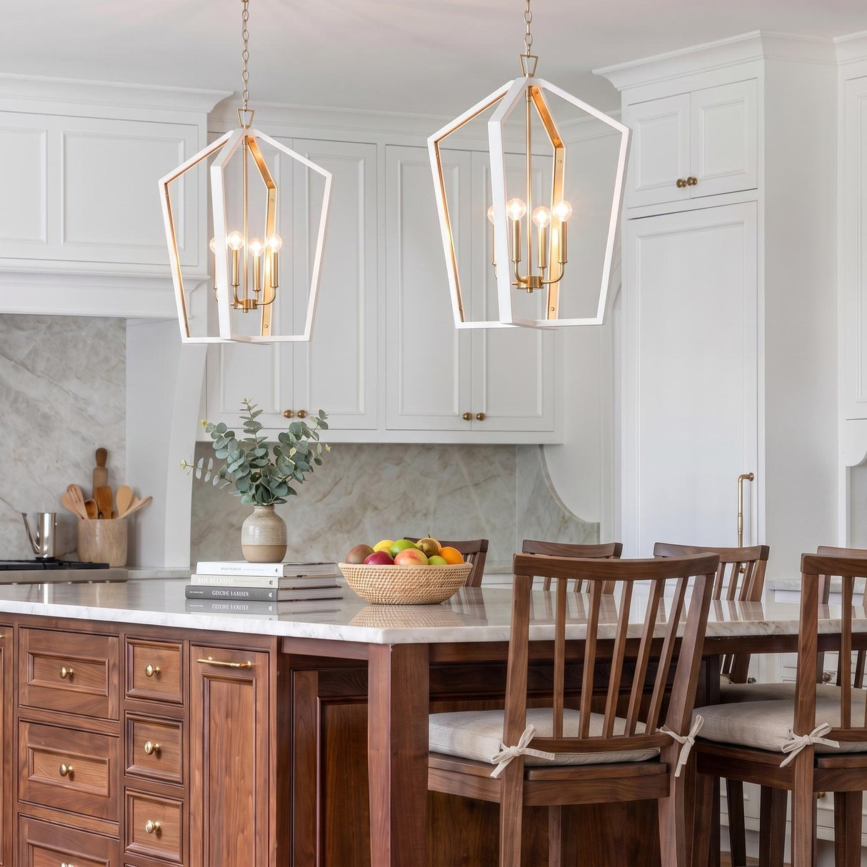 A modern farmhouse kitchen features two Talin Lantern Pendants in white and matte brass suspended over a walnut island with white marble and matching backsplash.