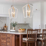 A modern farmhouse kitchen features two Talin Lantern Pendants in white and matte brass suspended over a walnut island with white marble and matching backsplash.
