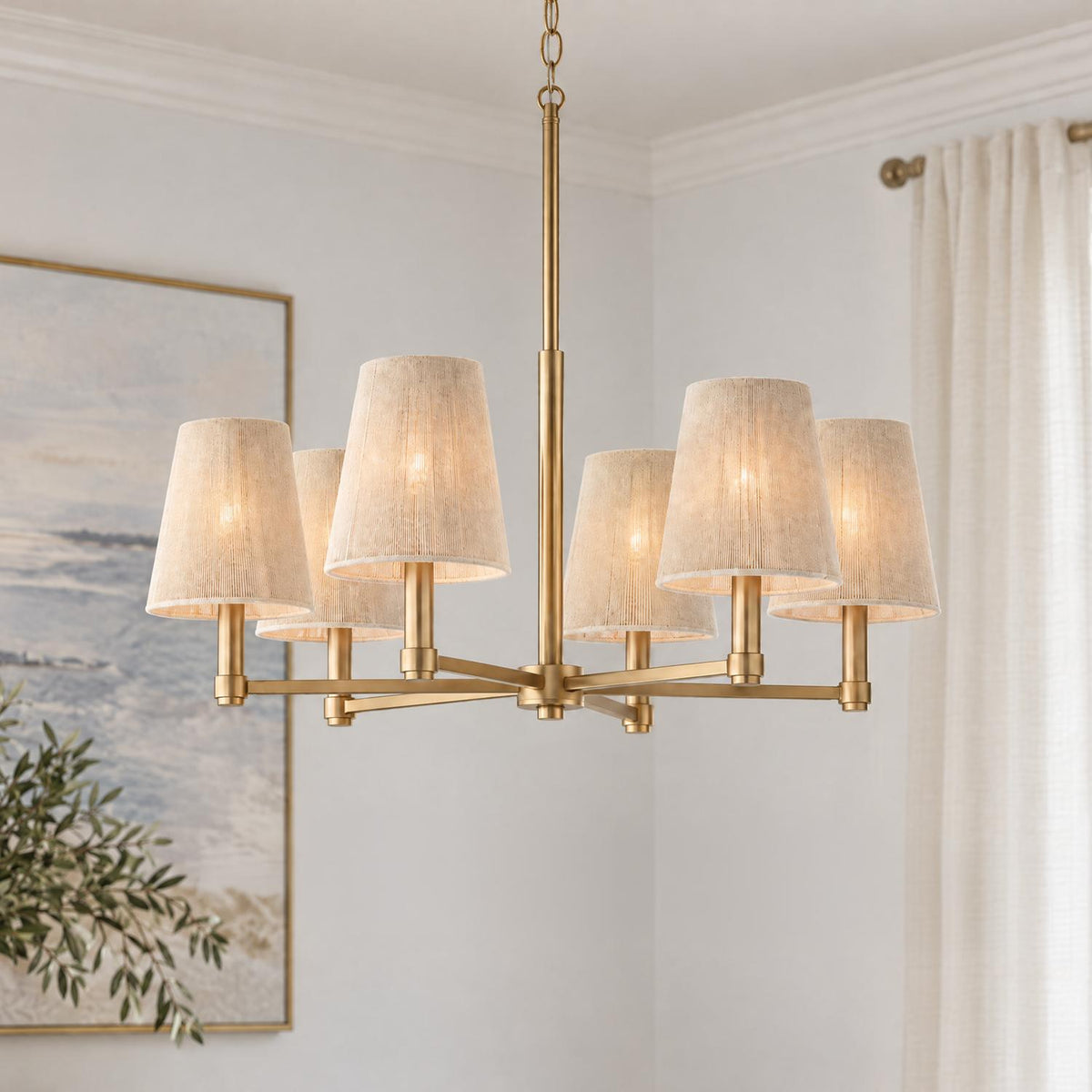 A transitional dining room featuring the Evren 6 Light Chandelier in matte brass with natural rope shades near framed coastal wall art and white curtains.