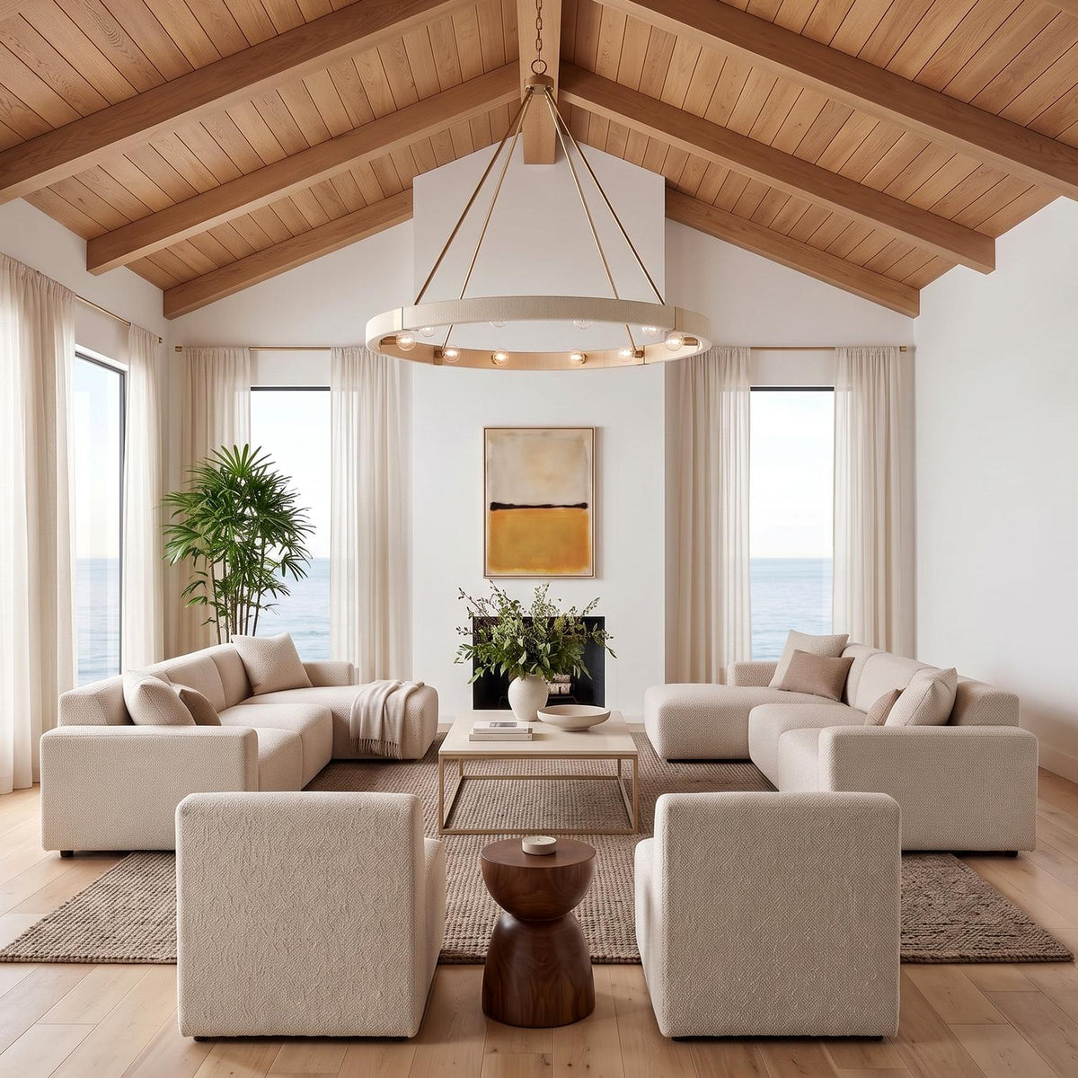 A coastal living room with the Saltair Ring Chandelier in matte brass and natural rope hanging from a vaulted wood ceiling above beige sectional sofas.