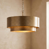 A transitional foyer with the Reed Pendant 21" in Textured Brushed Brass hanging from the ceiling center against beige textured plaster walls with soft ambient light.