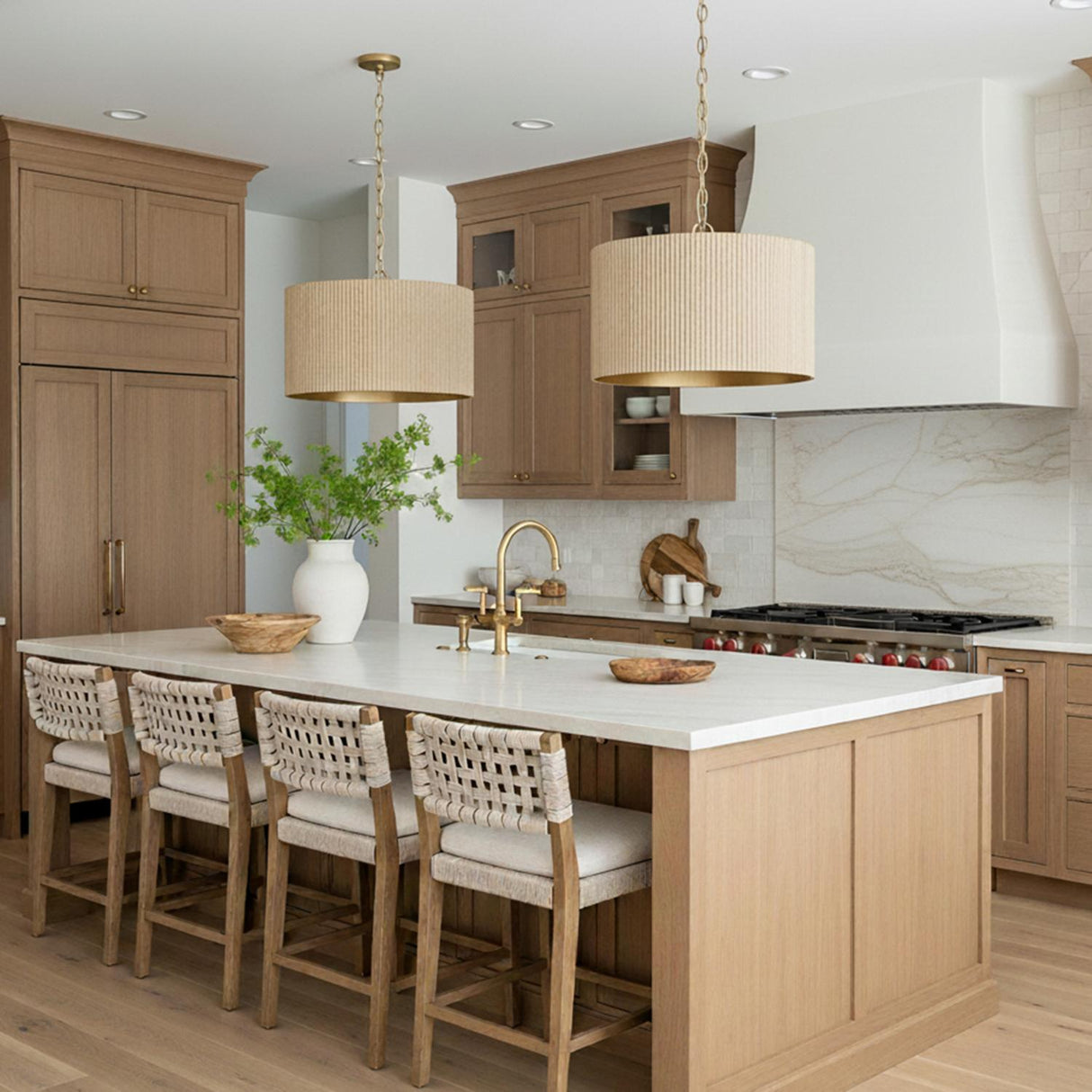 A transitional kitchen featuring two Leery Pendant 20", Whitewash and Matte Brass fixtures over the island with light wood cabinets and a white marble backsplash.