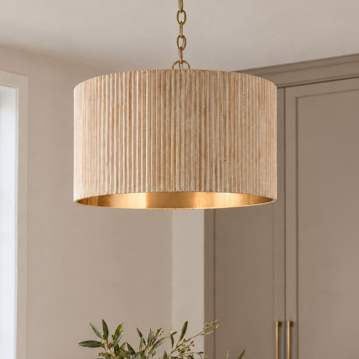 A transitional dining room with the Leery Pendant 20", Whitewash and Matte Brass suspended above a table beside taupe cabinetry with brass handles.