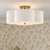 A transitional foyer features the Orla Semi-Flush 18-inch fixture in Brushed Gold with a scalloped white fabric shade against leaf patterned wallpaper.