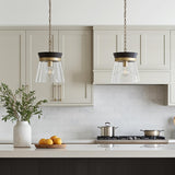 A transitional kitchen features two matte black and brass Maren Pendant 12 inch Ebony and Matte Brass fixtures over a white island and beige cabinets.