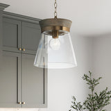 Maren Pendant light 12", Whitewash wood and Matte Brass details with clear glass, is shown in a kitchen with grey-green cabinets.