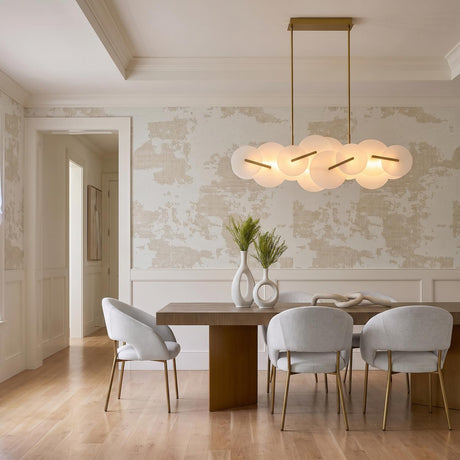 A transitional dining room with the Malya LED Linear Chandelier in brass and opal glass over a wood table under a coffered ceiling with wainscoting.