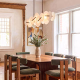 A contemporary dining room with the Malya LED Linear Chandelier in brass with opal glass suspended over a dark wood dining table and green upholstered chairs.