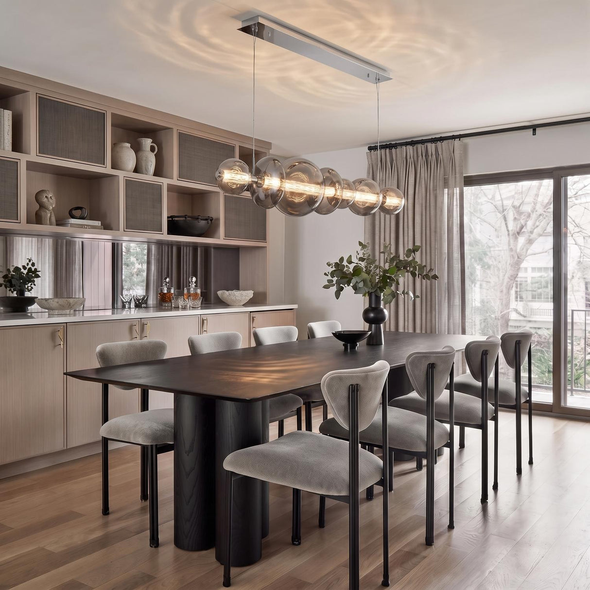 A contemporary dining room with the Elara LED 7 Light Linear Chandelier 56", Chrome and Smoke Glass over a dark wood table and gray chairs.