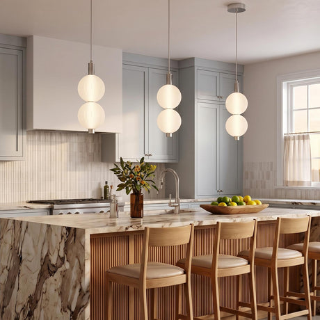 A contemporary kitchen featuring three Nola LED 2 Light Pendants in polished nickel and ribbed opal glass over a marble waterfall island with gray shaker cabinets.
