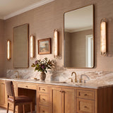 A transitional bathroom featuring the Inez LED Wall Sconce 36" in brass and alabaster flanking mirrors over a white marble vanity with wood cabinets.