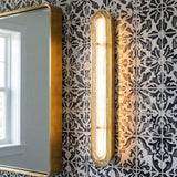 Vance LED Wall Sconce 38", Brass and Textured Glass linear geometric Wall Sconce in a Mediterranean Bathroom with a patterned tile wall.