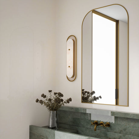 Vance LED Wall Sconce 22", in Brass and Alabaster finish, shown next to an arched mirror in a luxe bathroom with green marble slab sink and brass hardware.