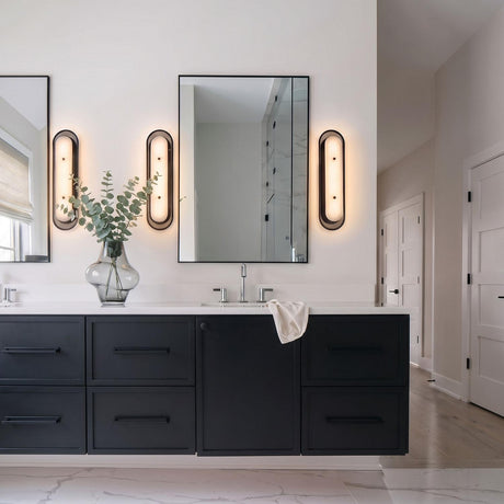 A contemporary bathroom featuring the Vance LED Wall Sconce in matte black and alabaster flanking mirrors above a black vanity with a white stone countertop.