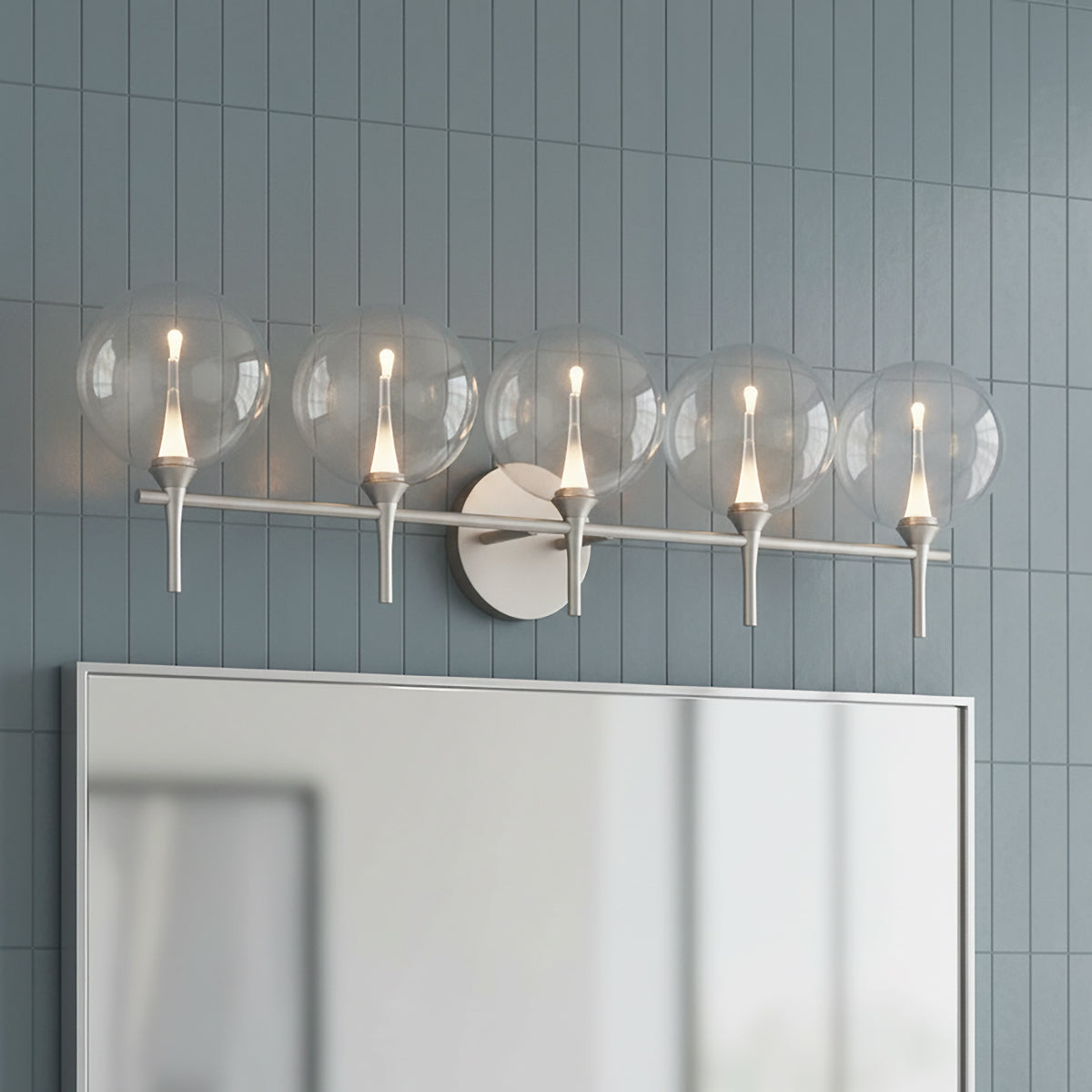 Eaton LED 5 Light Vanity, Satin Nickel and Clear Glass - A five-light vanity fixture with clear globe shades and satin nickel accents mounted above a mirror against a grey tiled wall.