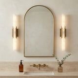 Delya LED Wall Sconce 22, Antique Brass and Alabaster, styled in a Contemporary Bathroom with travertine surfaces.