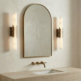 Delya LED Wall Sconce 22", Antique Brass and Alabaster linear Wall Sconce in a Modern Bathroom with an arched mirror and travertine vanity.